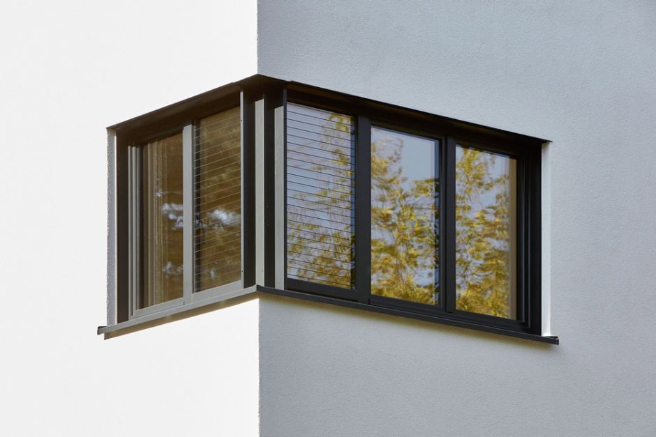 Ecke einer äußeren Hauswand mit schwarzem Eckfenster und weißer Fassade