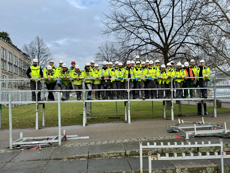 Viele Friedrich Wassermann Mitarbeiter in Baustellenkleidung auf einem Hochwasserpodest am Rhein